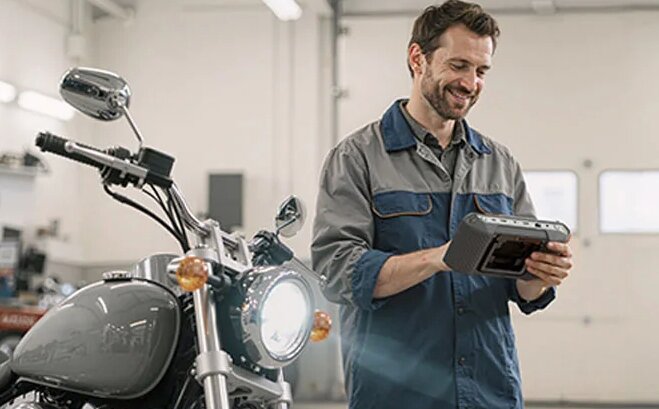 Mechanic using TOPDON tool to diagnose motorcycle.